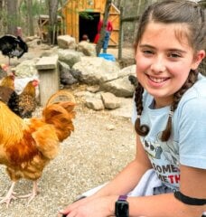 Dani at an animal sanctuary smiling next to a chicken