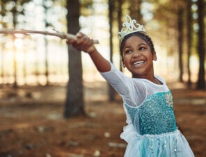 little girl dressed as a princess playing in the woods