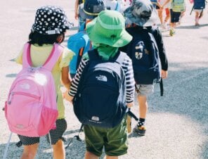 kids in a line at school with their school bags on and hats