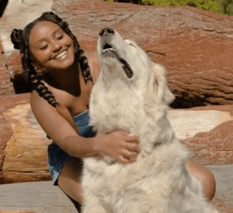 Dana Heath giving a white dog scratches outside in the sun