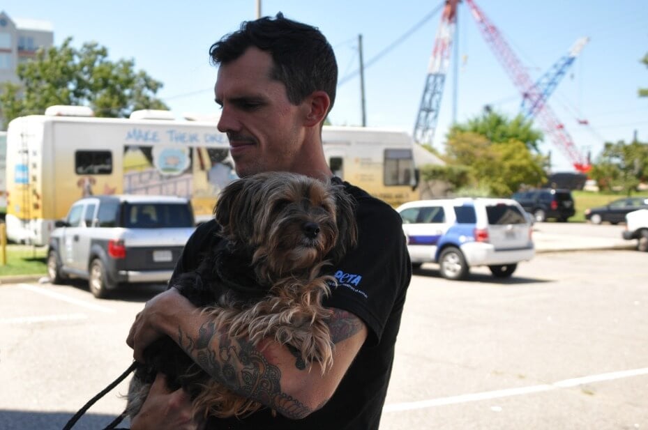 Community Animal Project staffer holding a dog in a parking lot