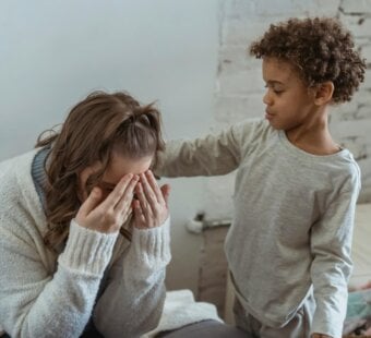 son is comforting his mom by touching her back while she cries.