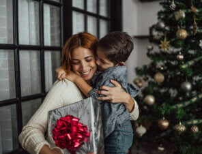 mother and son embracing each other while mom holds a gift.