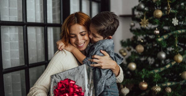 mother and son embracing each other while mom holds a gift.